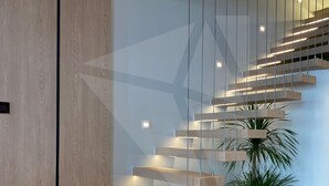 A modern staircase with wooden steps and integrated lighting, leading to a second floor. - Sun Grand Feria (Bai Chay)