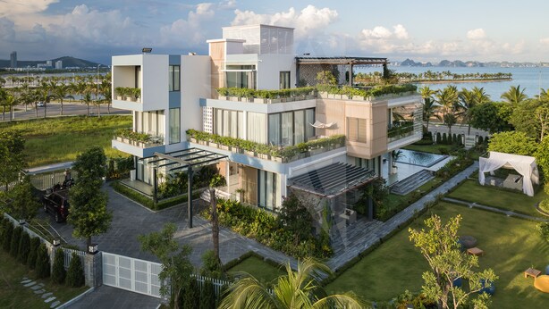 A modern multi-story building with a rooftop garden, a swimming pool, and a view of the sea. - Sun Grand Feria (Bai Chay)