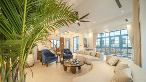 A spacious living room with a large sofa, two armchairs, a coffee table, and a staircase leading to an upper level. - Sun Grand Feria (Bai Chay)
