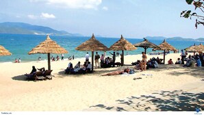 A beach with thatched umbrellas and people relaxing on the sand. - Sun Grand Feria (Bai Chay)