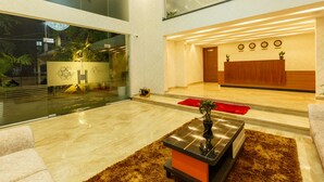 Um lobby moderno com balcão de recepção, uma grande parede de vidro e área de estar com uma mesa de centro.