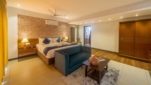 Quarto de hotel moderno com uma cama grande, um sofá, uma mesa pequena e um guarda-roupa.