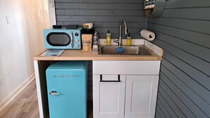 Una kitchenette compacta con microondas, pileta y espacio de almacenamiento.