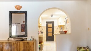 A hallway with a wooden cabinet, a mirror, and a striped bag. - Villa Sarrène (Nianing)