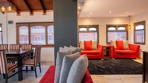 Ein modernes Wohnzimmer mit Essbereich, ausgestattet mit einem roten Sofa, grauen Kissen und gestreiften Stühlen.