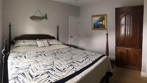 A bedroom with a bed, a wooden wardrobe, a fish wall art, and a door. - Location Location Location walk to all the favorite Rockport  attractions  (Rockport)