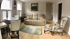 A living room with a beige sofa, a round coffee table, a patterned armchair, and a painting on the wall. - Location Location Location walk to all the favorite Rockport  attractions  (Rockport)