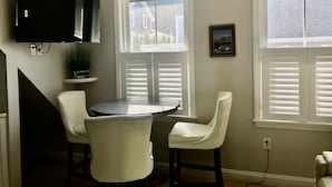 A dining area with a round table and two upholstered chairs, a mounted flat-screen TV, a potted plant, and a framed picture on the wall. - Location Location Location walk to all the favorite Rockport  attractions  (Rockport)