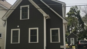 A two-story house with a dark exterior and white trim. - Location Location Location walk to all the favorite Rockport  attractions  (Rockport)