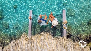 Una hamaca sobre una piscina con agua cristalina, rodeada de pastizal seco.