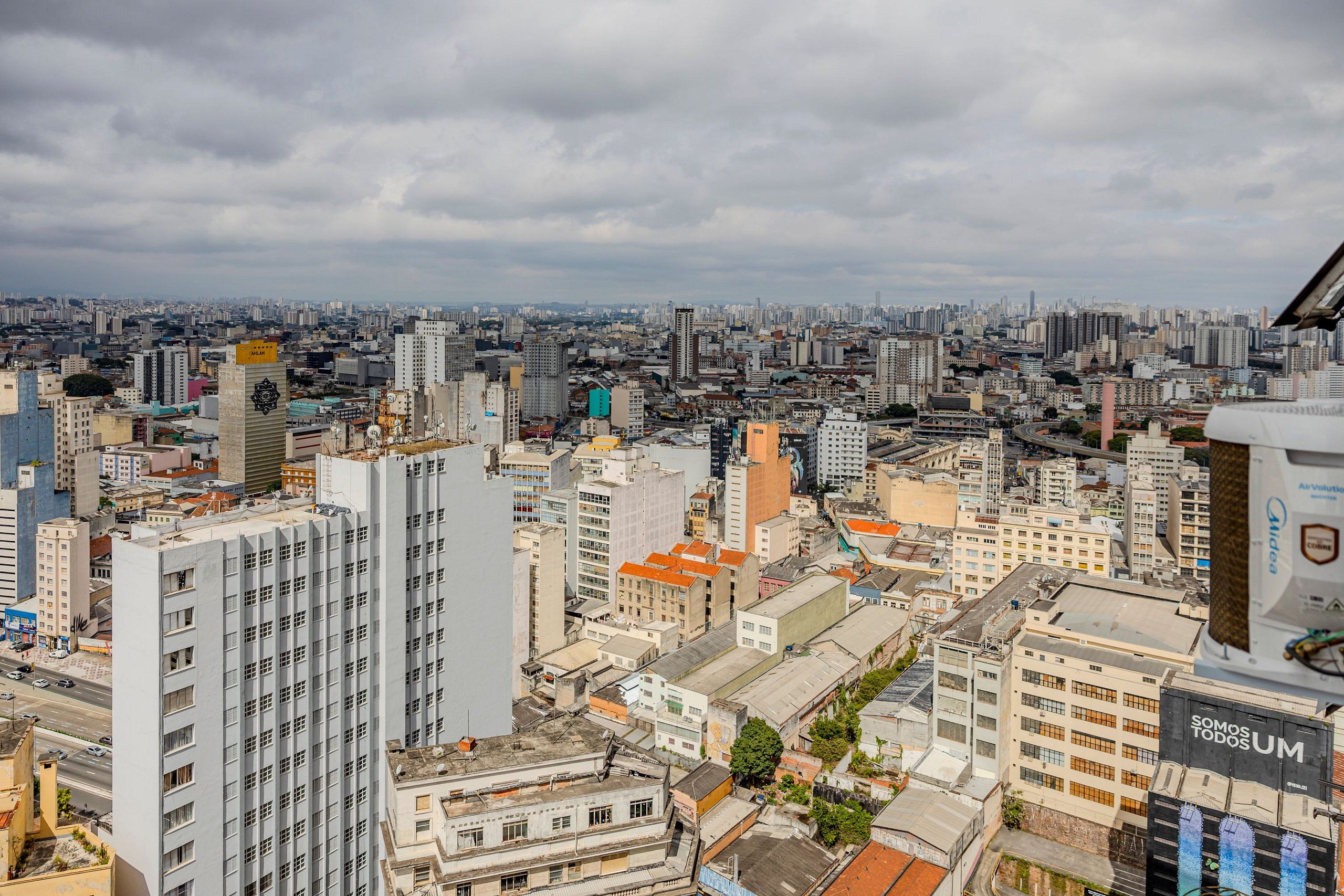 A cityscape with high-rise buildings, a prominent tower with a sign, and a billboard with text.