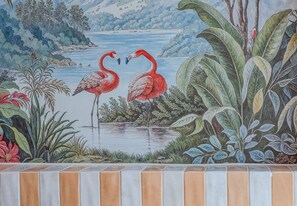 A mural with two flamingos, a body of water, and surrounding foliage. - Vossa Bossa Sky Mirante (São Paulo)