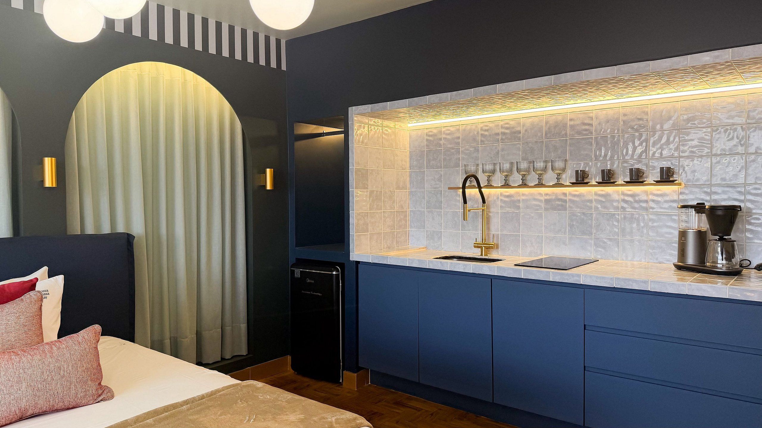 A compact hotel room with a bed, a small kitchenette, and a bathroom.