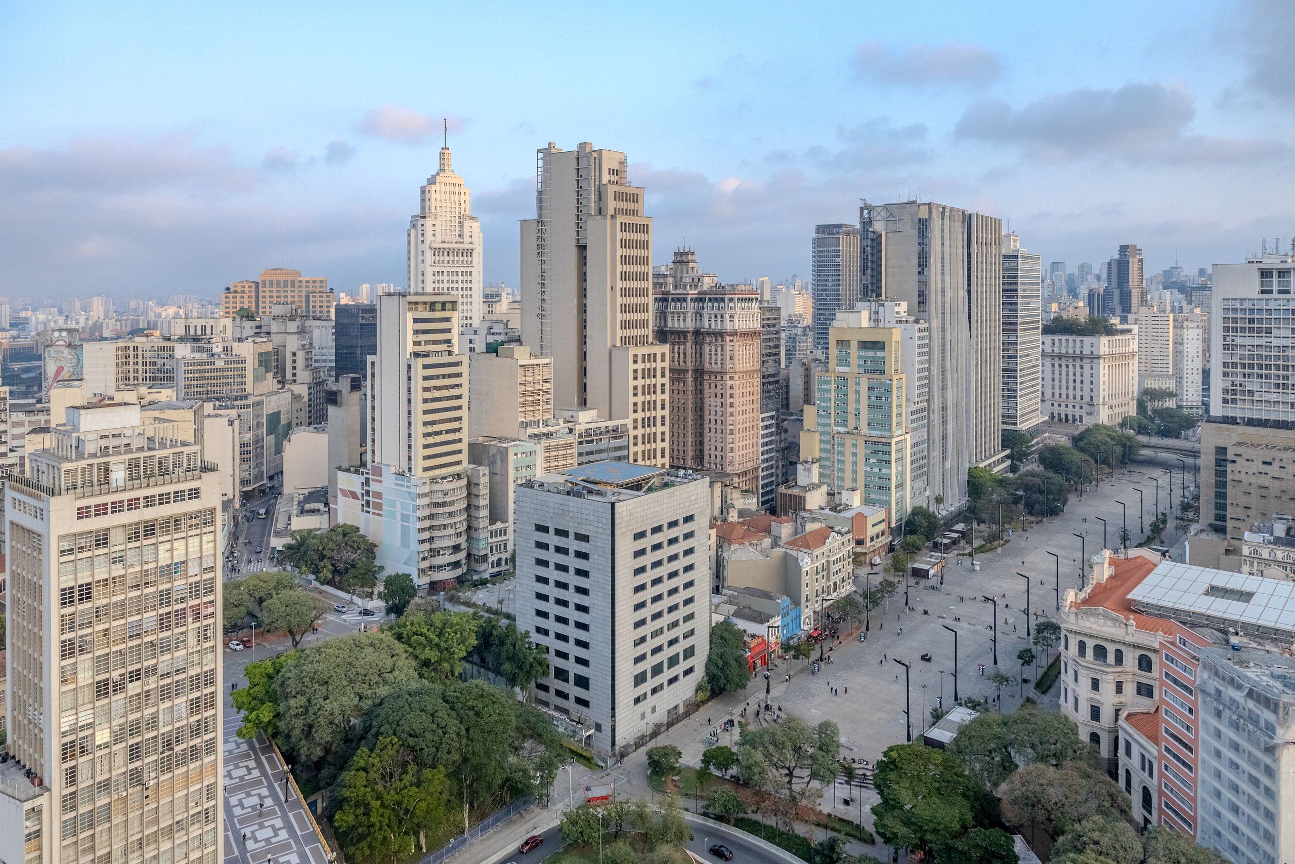 A cityscape with high-rise buildings, a central open square, and surrounding greenery.
