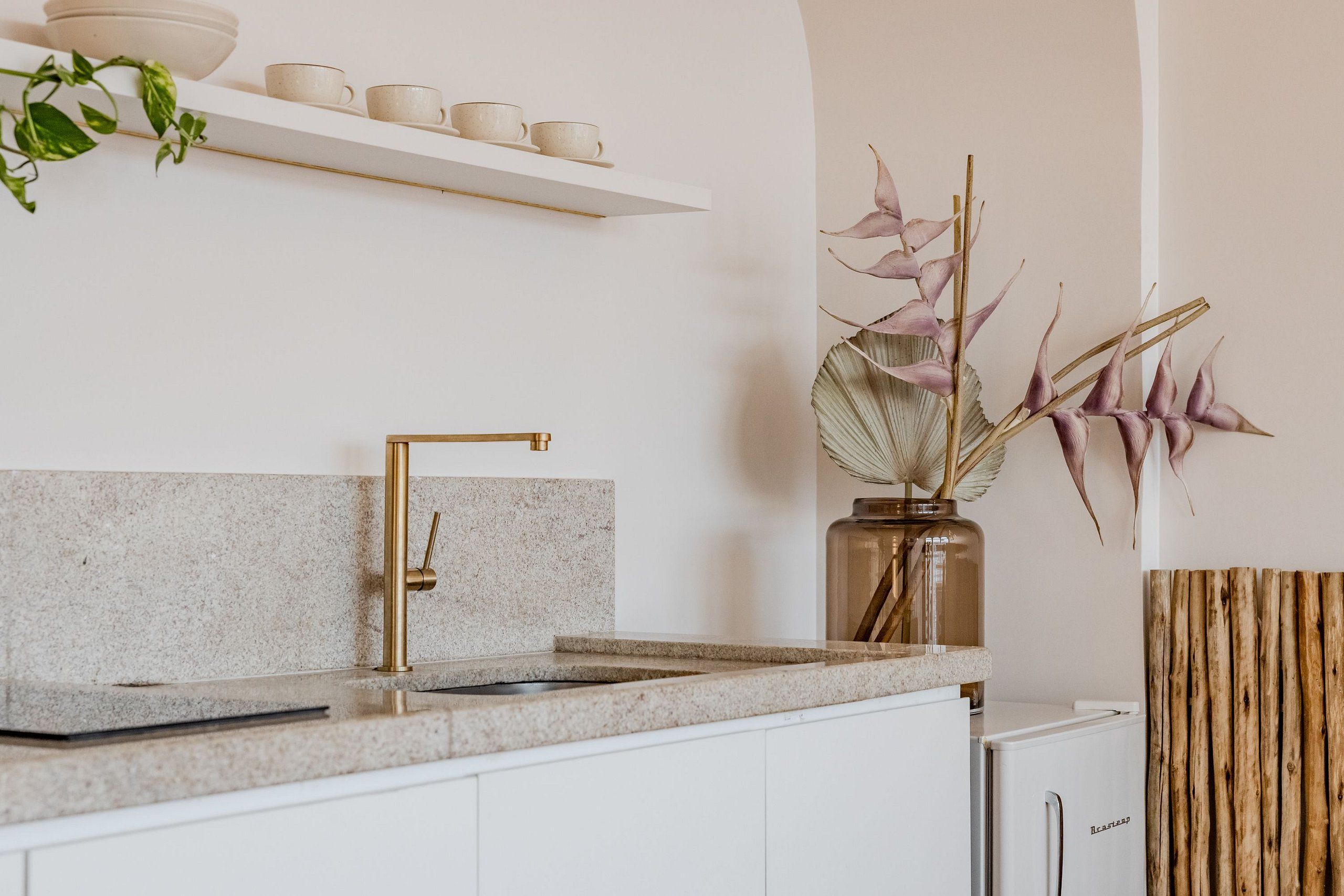 Eine Küche mit Granit Arbeitsplatte, einem goldenen Wasserhahn und einem weißen Kühlschrank.