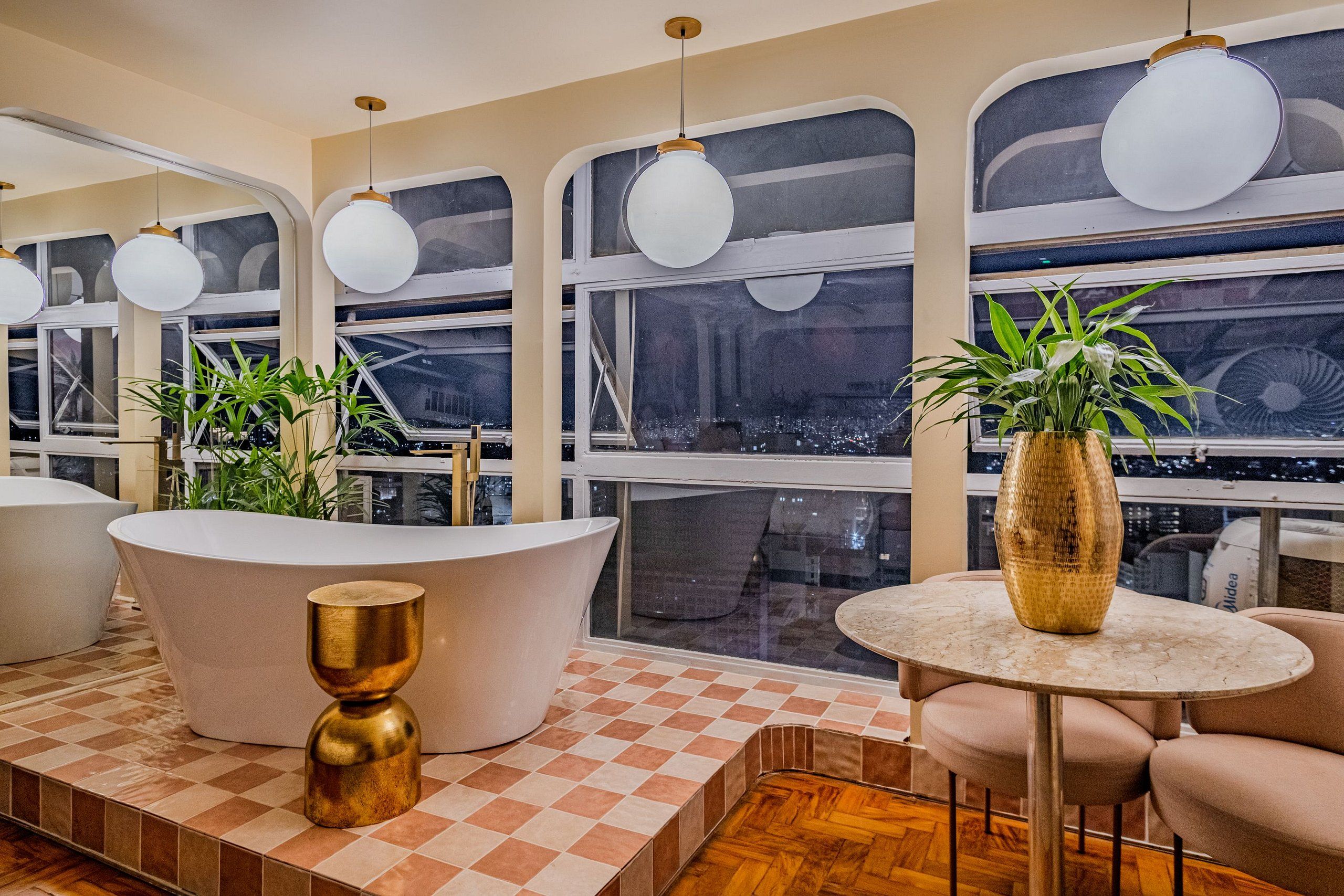 Een modern interieur met een groot bad, een ronde tafel met een vaas en meerdere hanglampen.