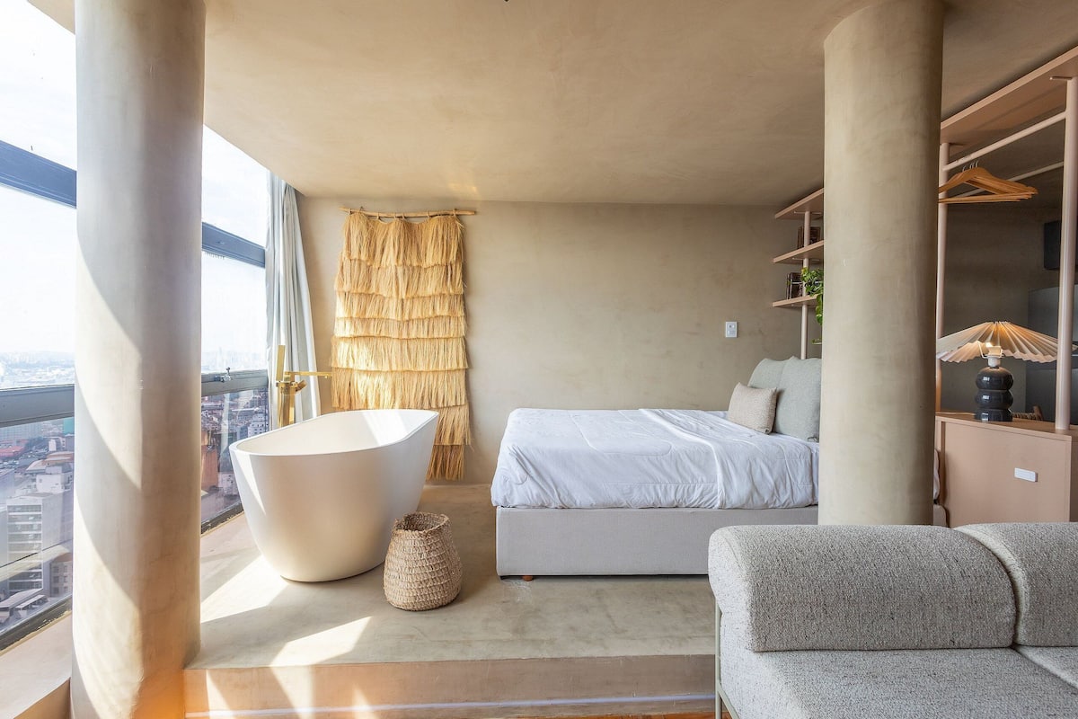 Un dormitorio moderno con un ventanal grande, una bañera, un sofá y una cama.