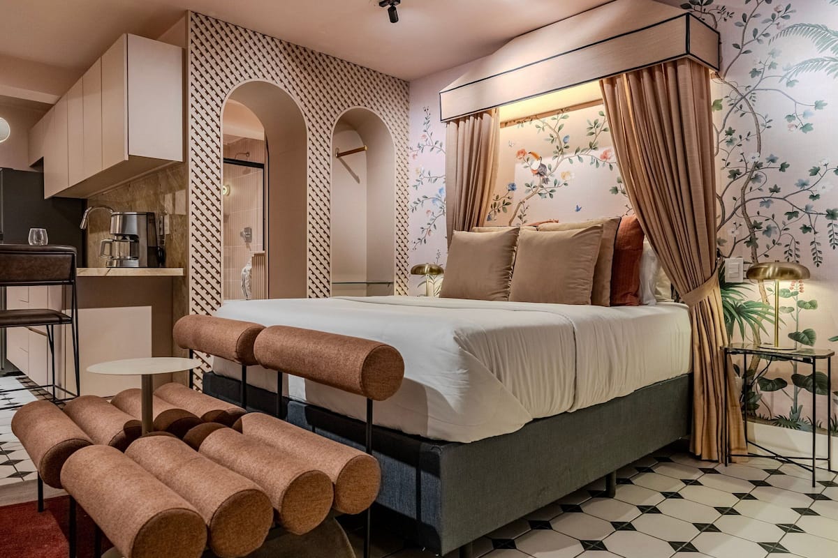 Un dormitorio moderno con cama, una mesita, un banco y una cafetera.
