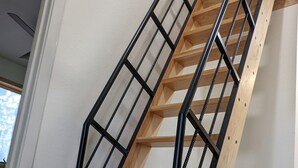 Eine Wendeltreppe aus Holz mit schwarzen Metallgeländern in einem Raum mit weißen Wänden und einem Betonboden.