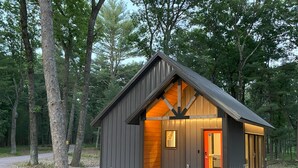 Eine kleine, moderne Holzhütte mit geneigtem Dach und einer roten Tür.