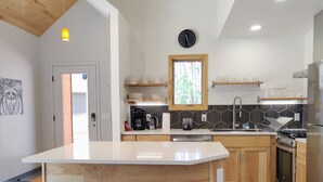 Eine moderne Küche mit einer zentralen Kochinsel, Holzschränken, einem Einbauofen und einer Kaffeemaschine.