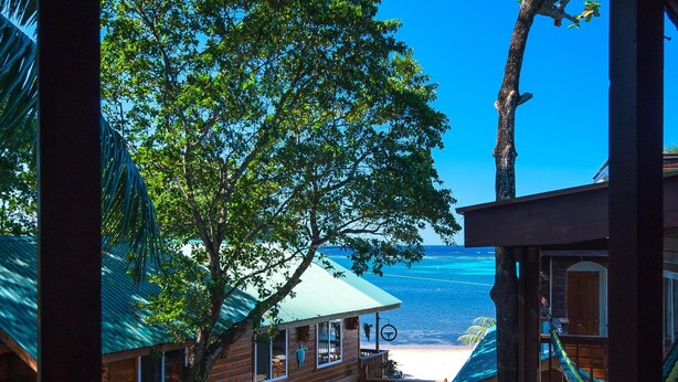 A wooden building with a balcony overlooking a beach and ocean.