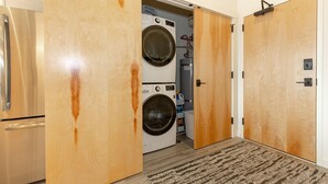 Un lavadero con lavadora y secadora de carga frontal, puertas de madera y un refrigerador de acero inoxidable.