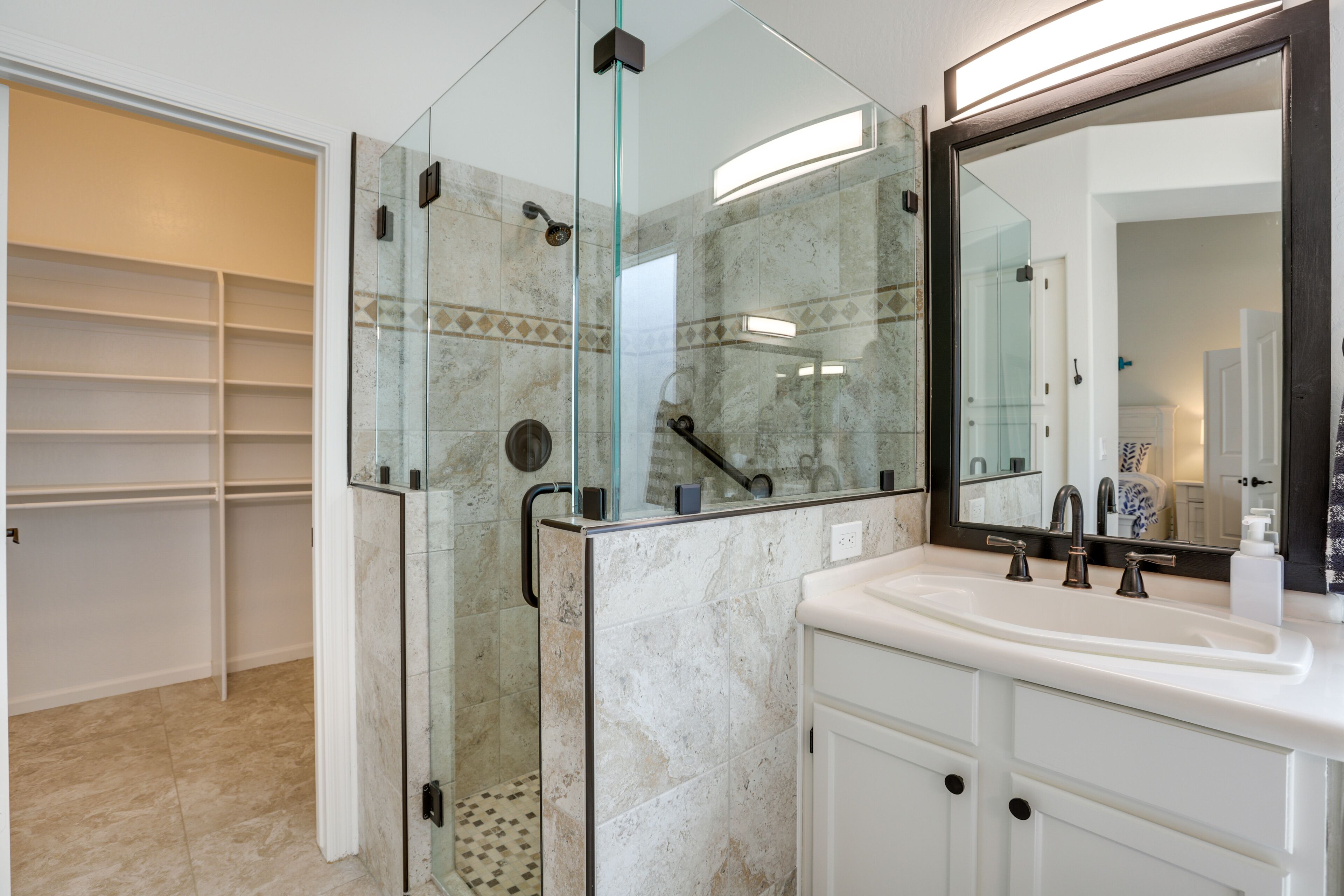 A modern bathroom with a glass-enclosed shower, a white sink, and a large mirror.