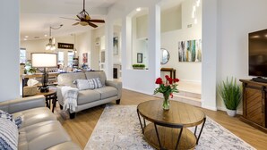 A spacious living room with a sofa, a coffee table, and a TV. There is a kitchen in the background with a dining area. - Upscale Golfer's Oasis w/ Pool & Spa in Cave Creek (Cave Creek)