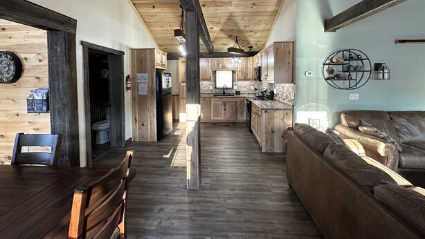 A modern kitchen with wooden cabinets, a central island, and a dining area with a wooden table and chairs.