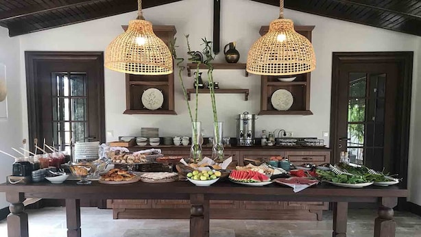 Una mesa de comedor con diversas opciones de comida y dos lámparas colgantes de mimbre.