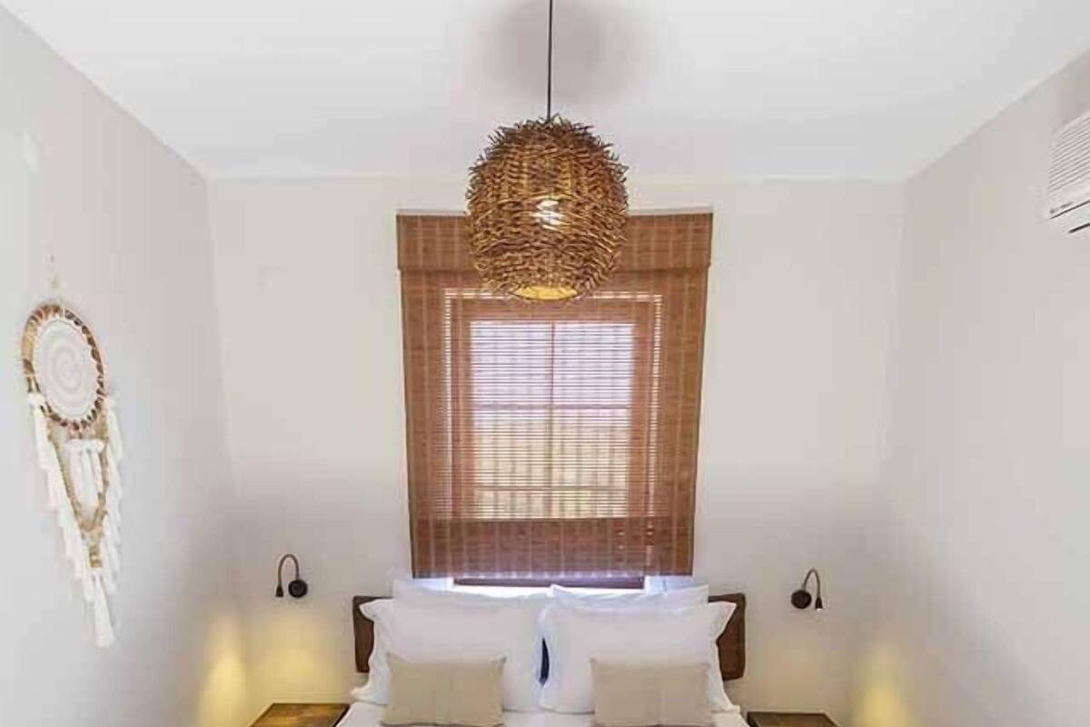 Un dormitorio con una cama grande, una lámpara colgante y una ventana con persianas.