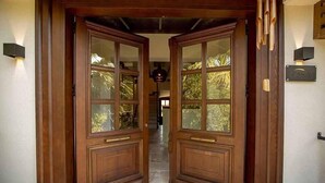 Una puerta doble de madera con paneles de vidrio y un pomo de latón.