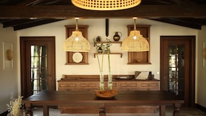 Una mesa de comedor de madera con un centro de mesa de mimbre, rodeada de armarios de madera y una lámpara colgante de mimbre.