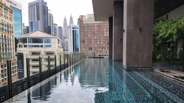 Una piscina en la azotea con vista a la ciudad, rodeada de rascacielos.