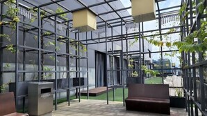 Un espacio exterior moderno con techo de vidrio, zonas de estar y vegetación.