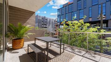 A balcony with a potted plant, a metal table, and a patterned rug.