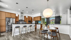 A modern kitchen with wooden cabinets, stainless steel appliances, and a central island with bar stools. - Tempe Lofts (Tempe)