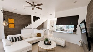 A modern living room with a white sofa, a round coffee table, and a ceiling fan. - Tempe Lofts (Tempe)