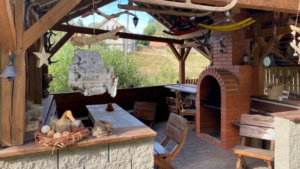 A rustic outdoor dining area with a brick oven, wooden benches, and a stone table. - Family vacation home with 6 studio apartments. (Ceský Jiretín)