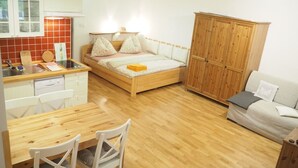 A compact bedroom with a wooden bed, a small kitchenette, a dining area with a wooden table and chairs, and a wardrobe. - Family vacation home with 6 studio apartments. (Ceský Jiretín)