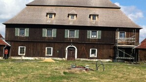 A large, two-story wooden house with a gabled roof and green shutters. - Family vacation home with 6 studio apartments. (Ceský Jiretín)