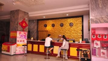 A hotel reception area with a marble column, a golden textured wall, and a red Chinese character decoration.