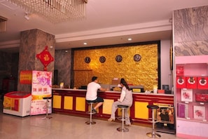 A hotel reception area with a marble column, a golden textured wall, and a red Chinese character decoration. - Bailong Hotel (Pingyin)