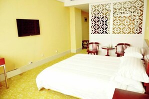 A hotel room with a bed, a TV, a small table, two chairs, and a decorative partition. - Bailong Hotel (Pingyin)