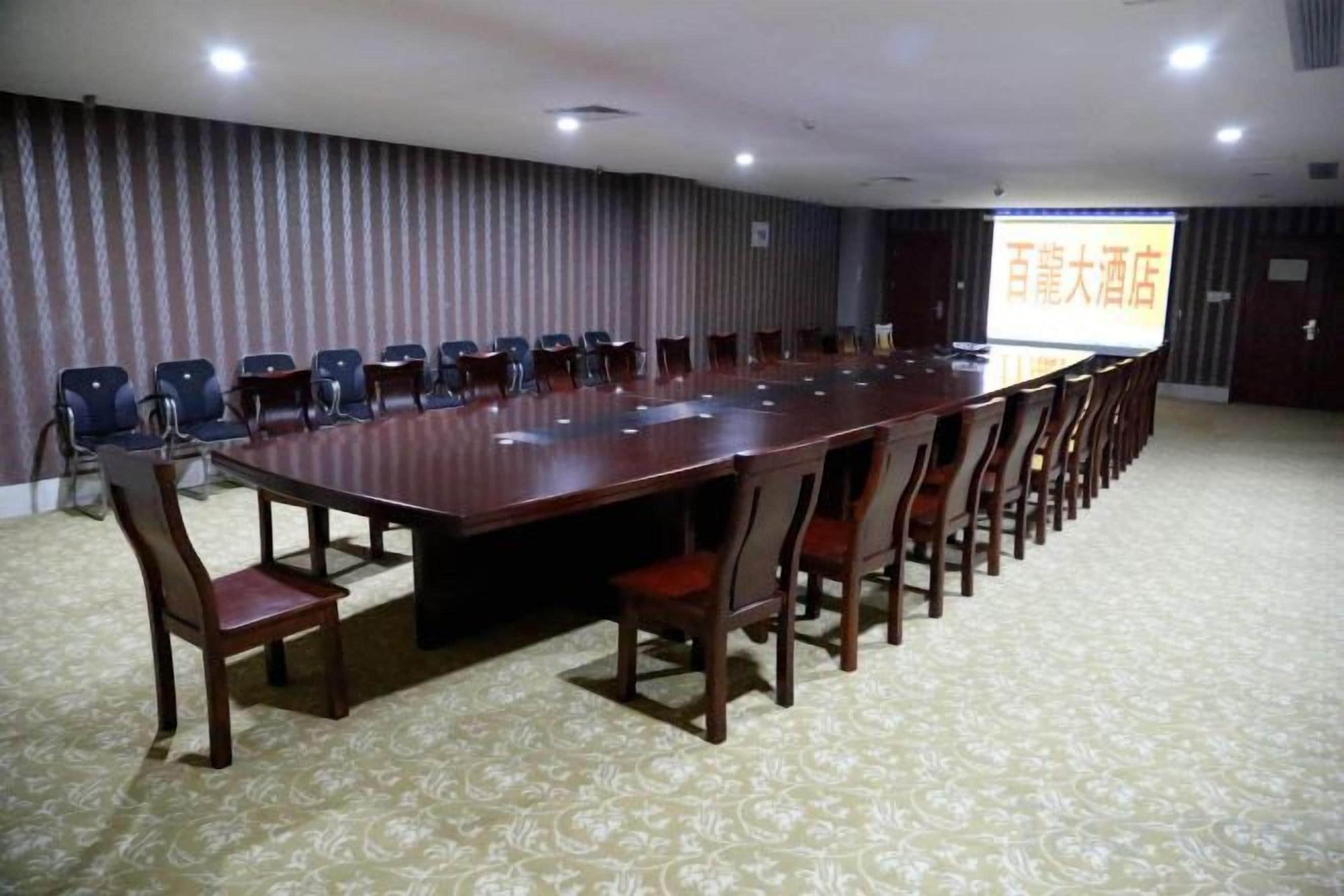 Une salle de conférence équipée d’une longue table, de chaises et d  ’un écran de projection.