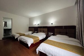 A hotel room with four beds arranged in a row, each with a headboard and bedside tables.