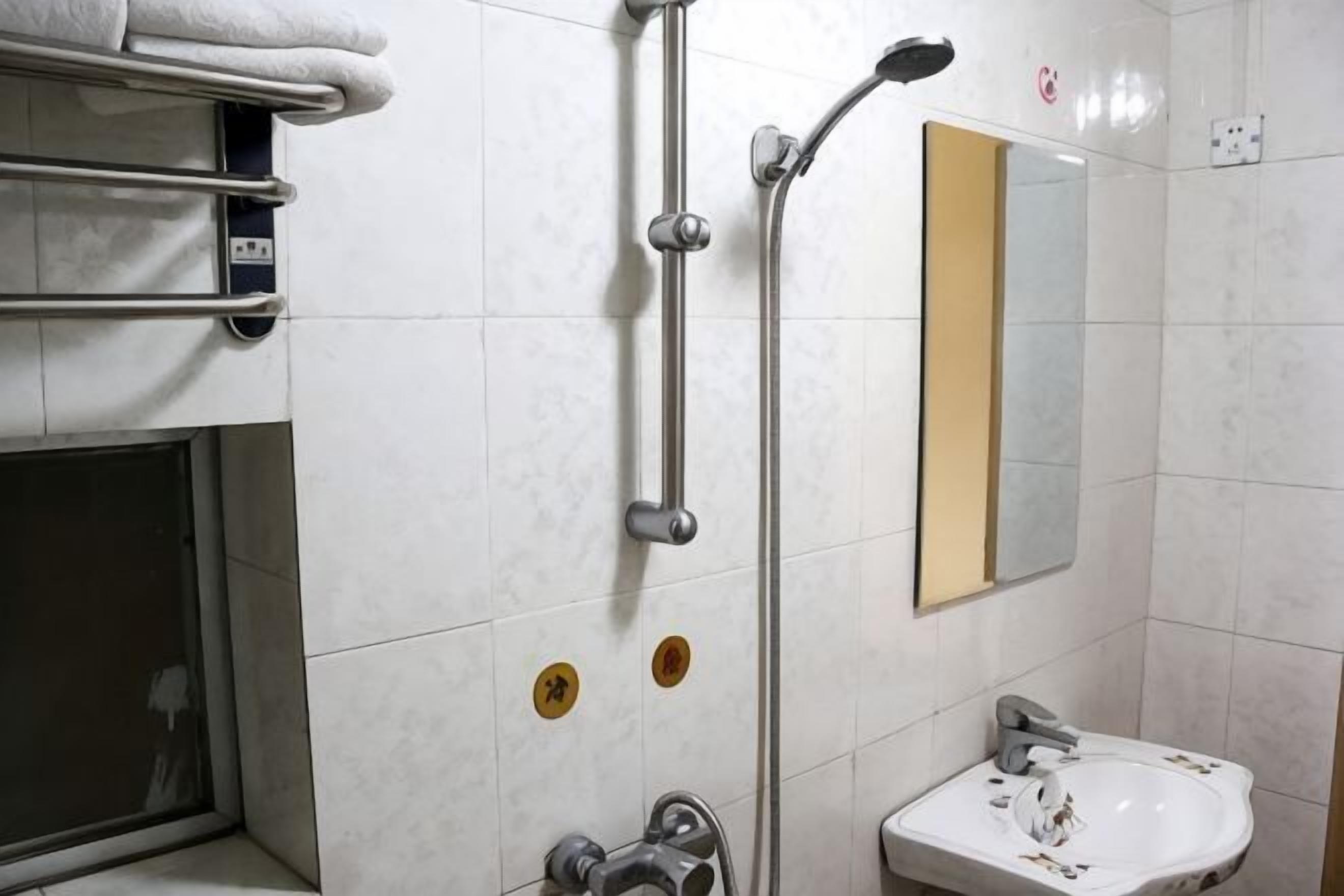 A bathroom with a shower, a sink, a towel rack, and a mirror.