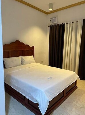 Enjoy a restful stay in this cozy room with a single bed, window, and air conditioning unit.