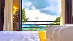 A hotel room with a bed, a yellow pillow, and a view of a mountain landscape through a window. - Cozy B&B Mountain Getaway (Cebu City)